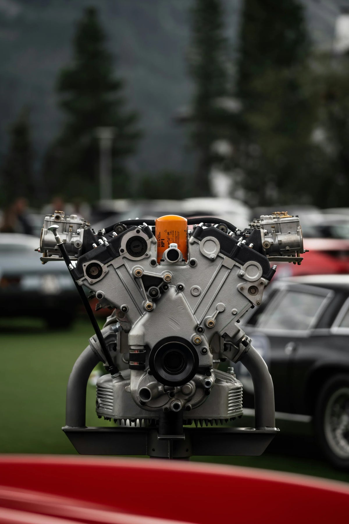 High-performance V8 engine with orange oil filter, displayed outdoors at car show