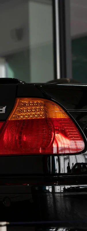 Close-up of a black European car's rear taillight with amber turn signal, showcasing premium auto part detail.