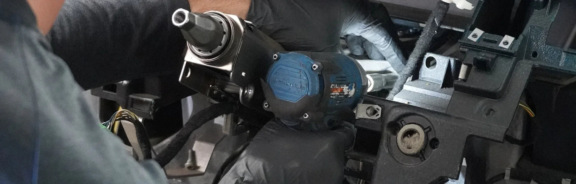 Mechanic installing OEM auto part with power tool in European vehicle engine bay